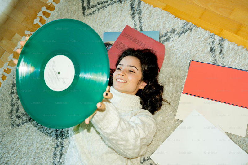 Person lying on a colorful rug holding a green vinyl record
